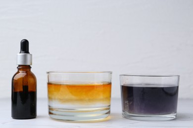 Photo of Iodine starch test. Bottle of iodine, glass with water containing starch and regular one on white table