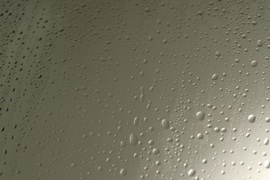 Water drops on grey glass surface, closeup