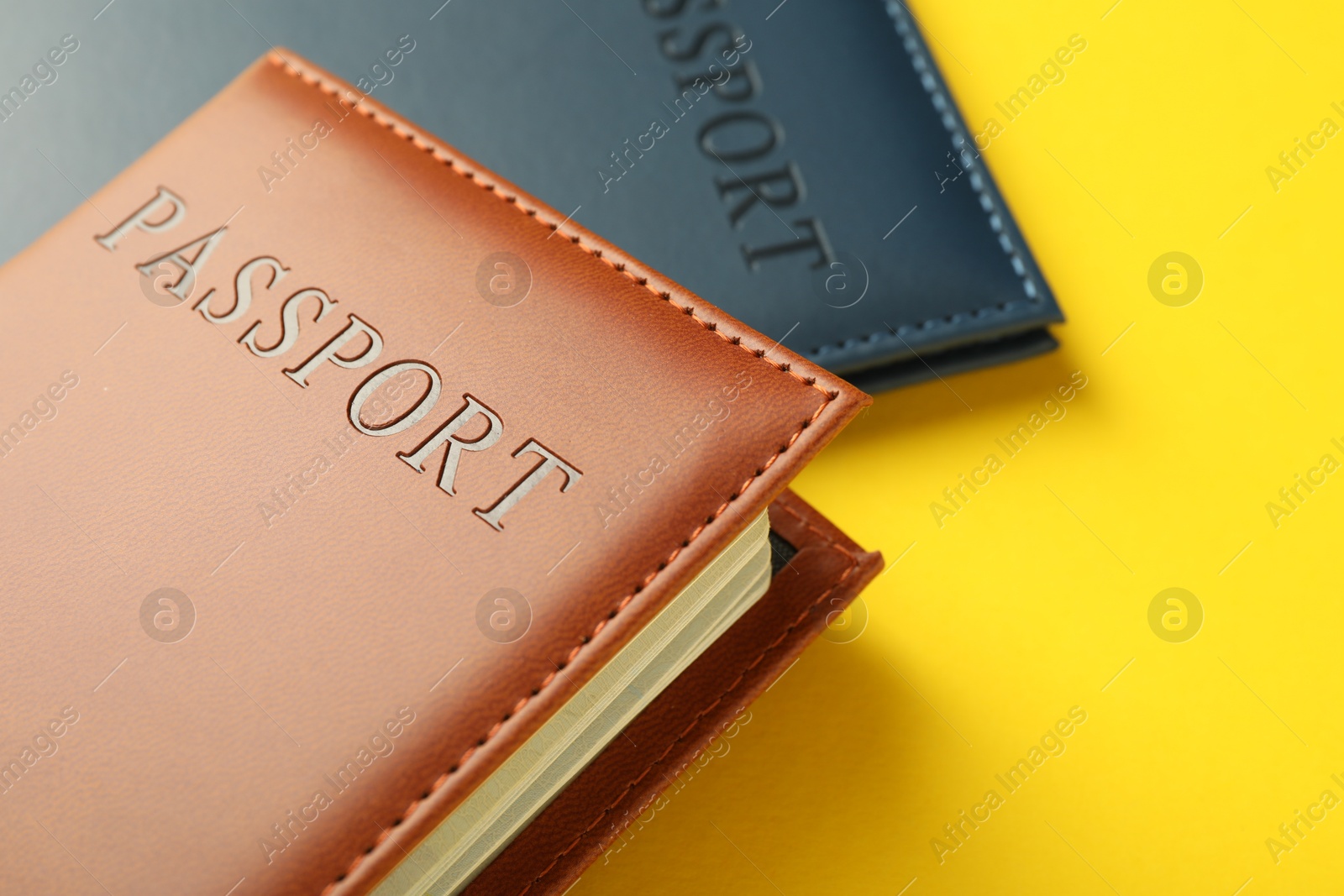 Photo of Passports in color covers on yellow background, closeup