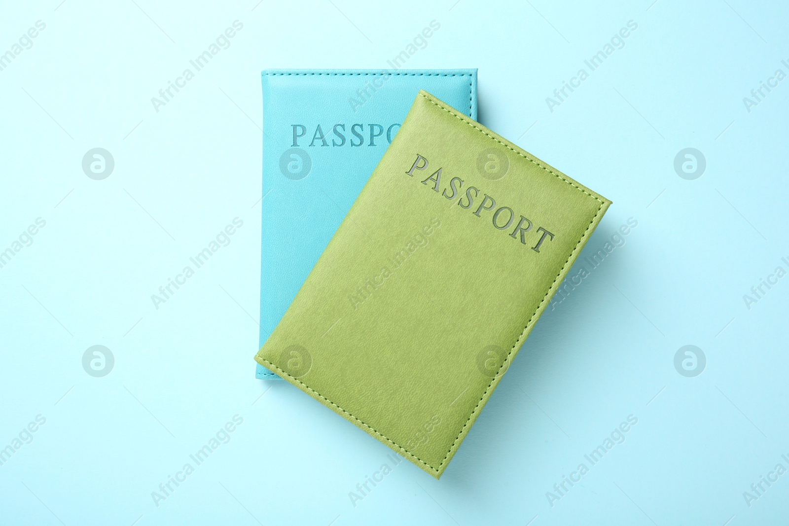 Photo of Passports in color covers on light blue background, top view