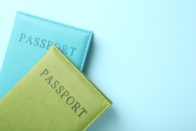 Photo of Passports in color covers on light blue background, top view. Space for text