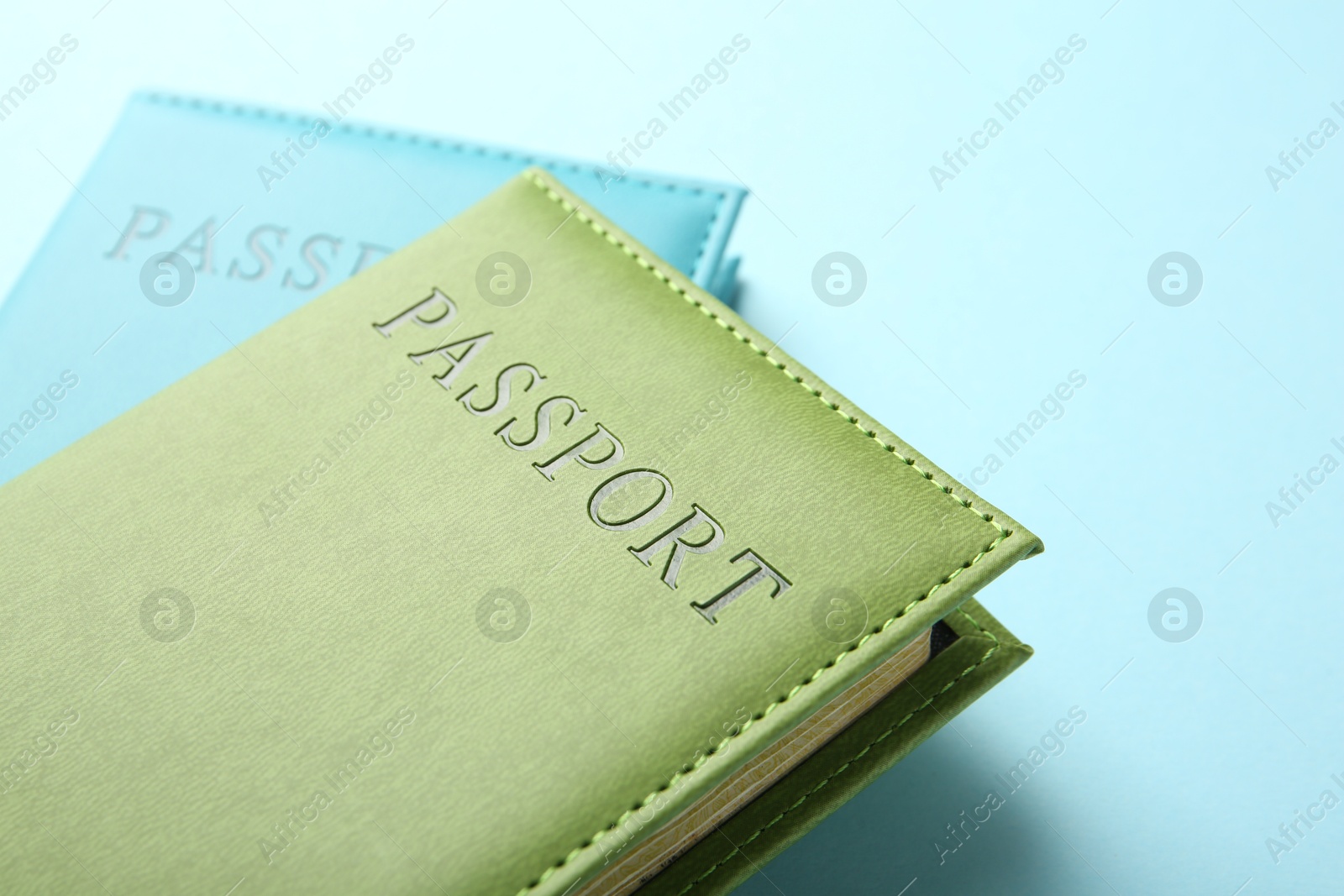 Photo of Passports in color covers on light blue background, closeup