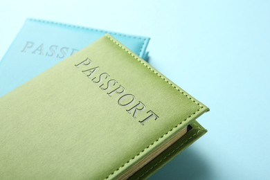 Photo of Passports in color covers on light blue background, closeup