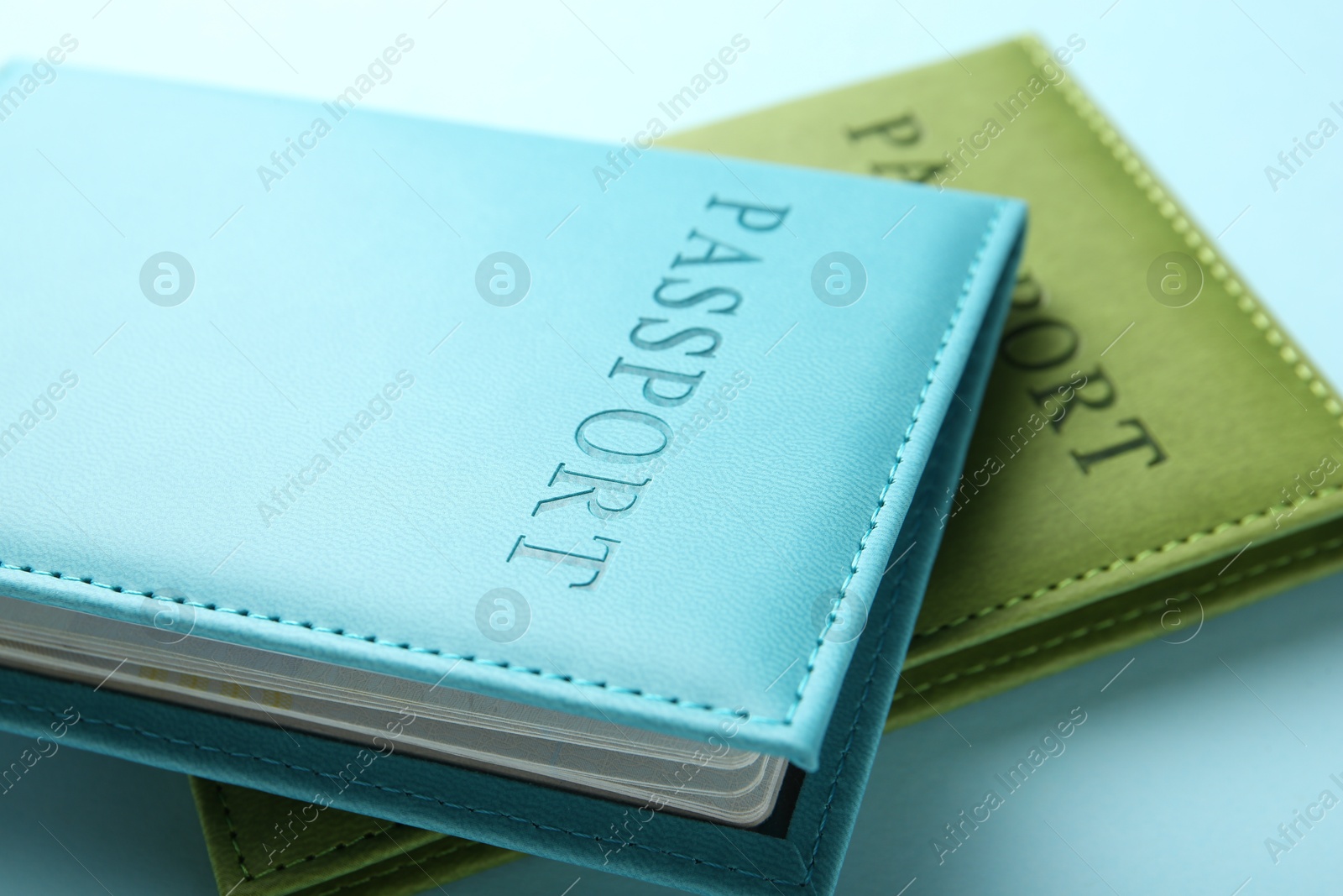 Photo of Passports in color covers on light blue background, closeup