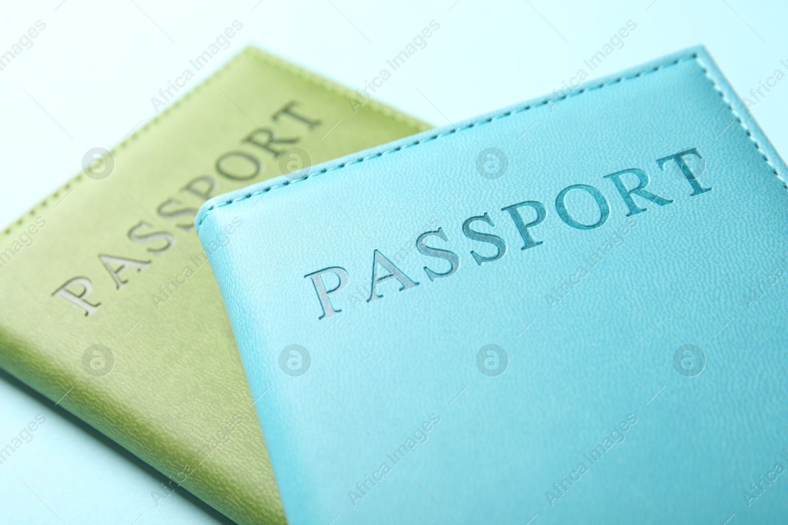 Photo of Passports in color covers on light blue background, closeup