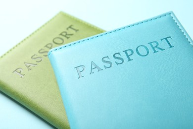 Photo of Passports in color covers on light blue background, closeup