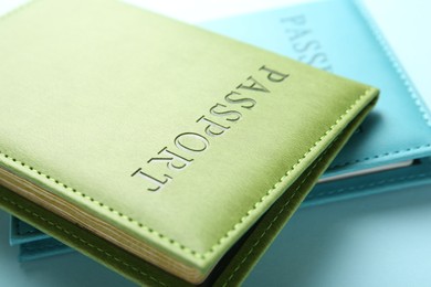 Photo of Passports in color covers on light blue background, closeup