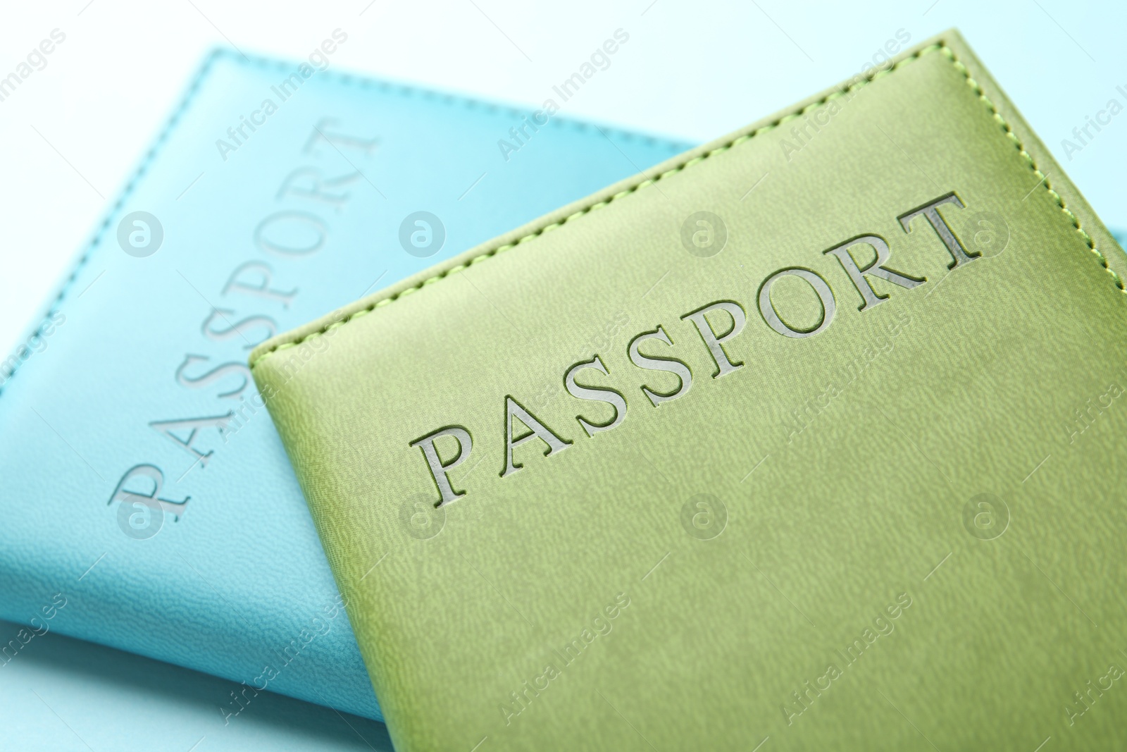 Photo of Passports in color covers on light blue background, closeup