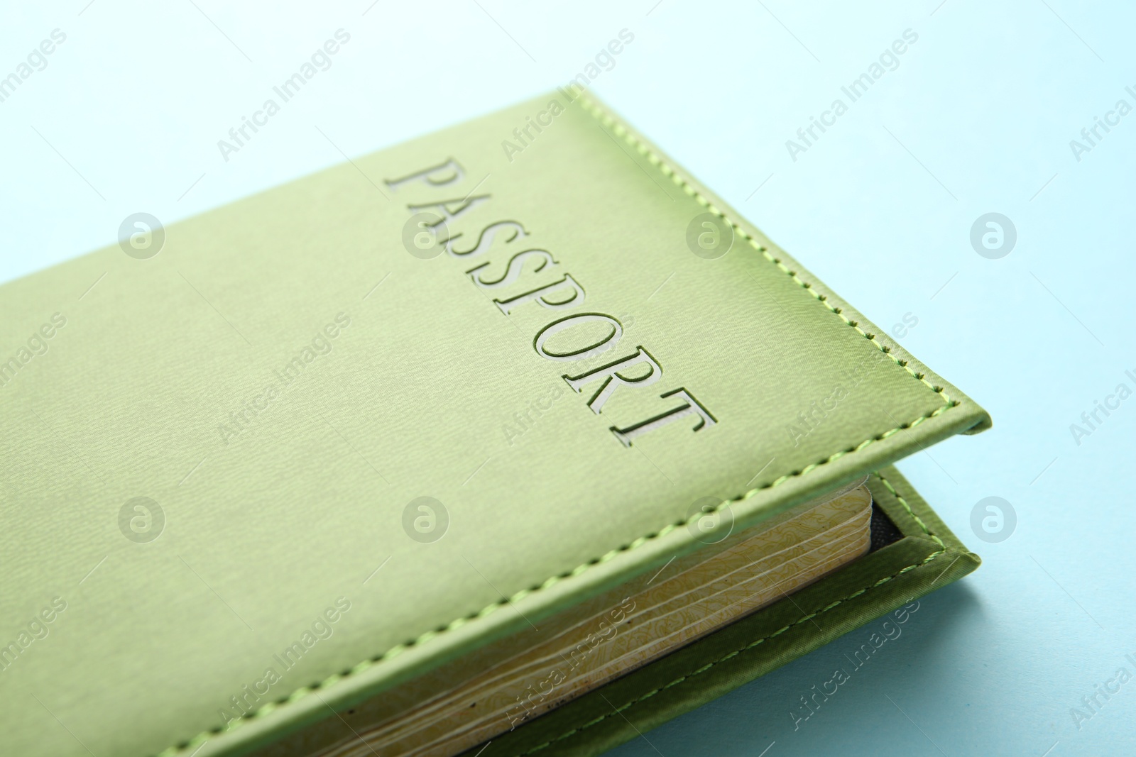 Photo of Passport in green cover on light blue background, closeup