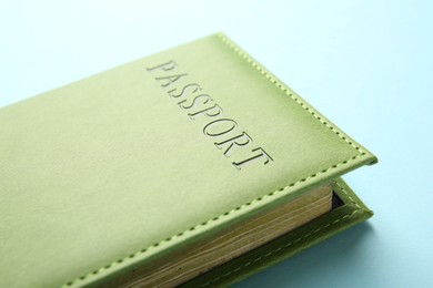 Photo of Passport in green cover on light blue background, closeup