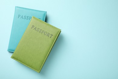 Photo of Passports in color covers on light blue background, top view. Space for text