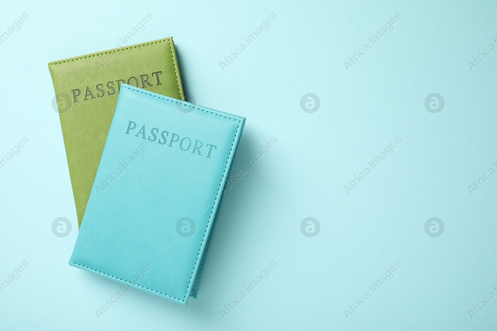 Photo of Passports in color covers on light blue background, top view. Space for text