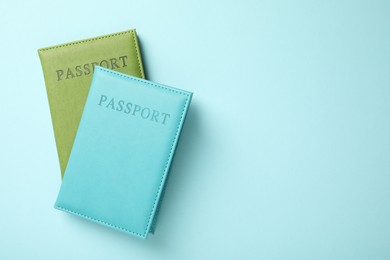 Photo of Passports in color covers on light blue background, top view. Space for text