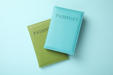 Photo of Passports in color covers on light blue background, top view