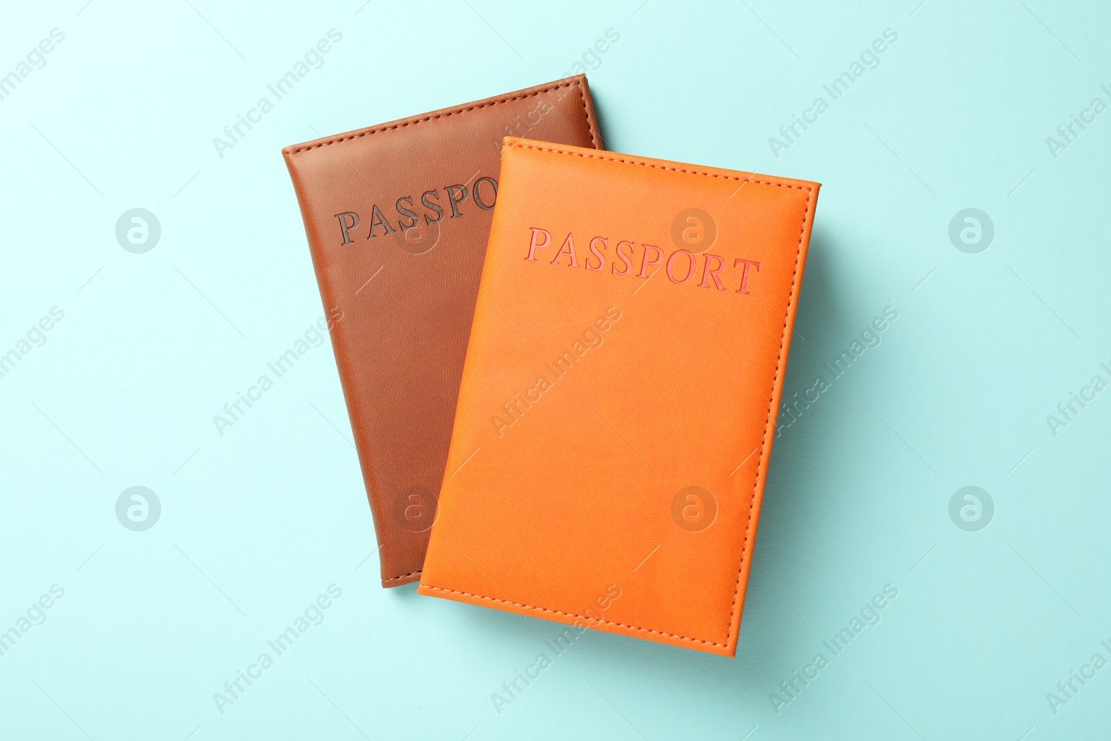 Photo of Passports in color covers on light blue background, top view