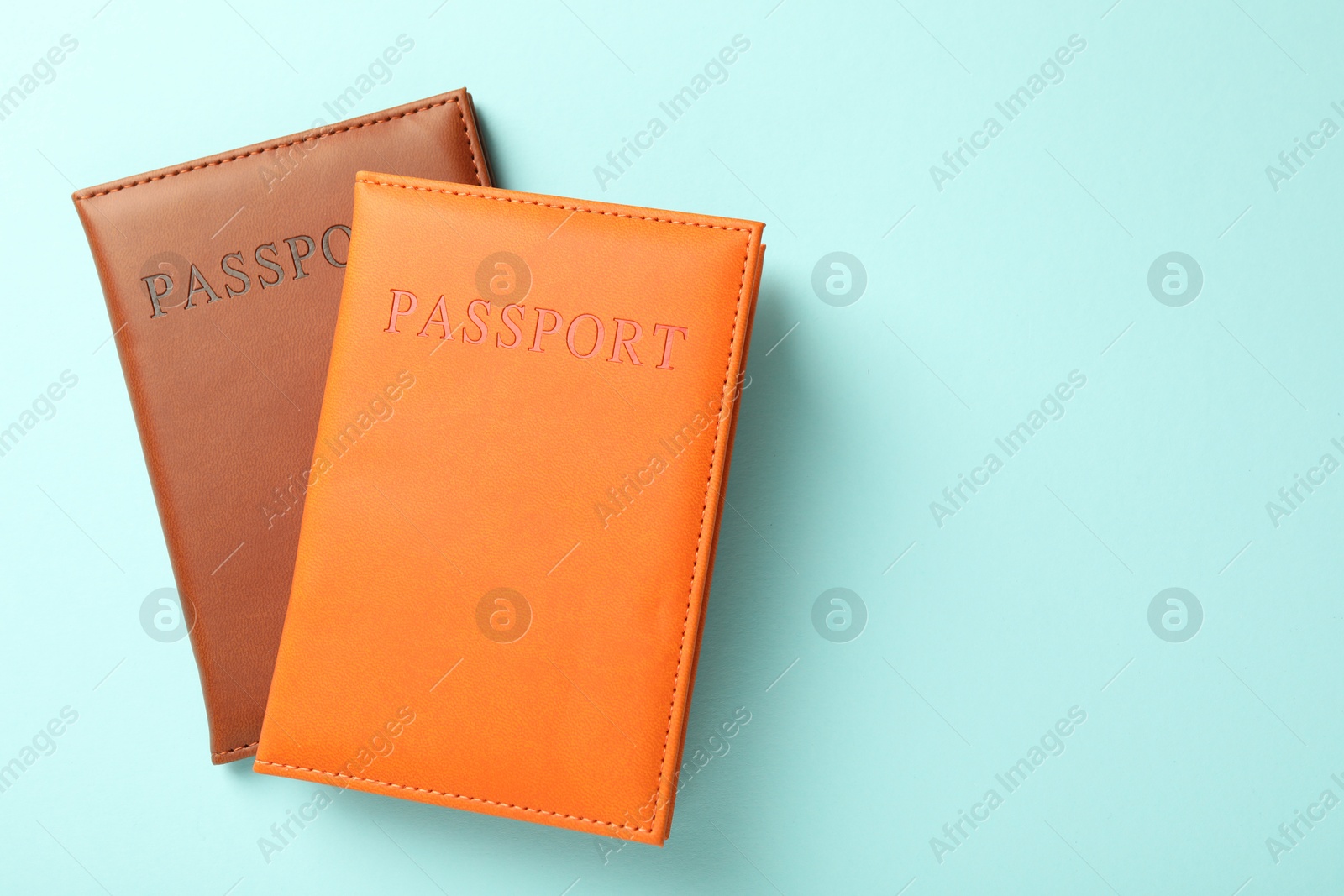 Photo of Passports in color covers on light blue background, top view. Space for text