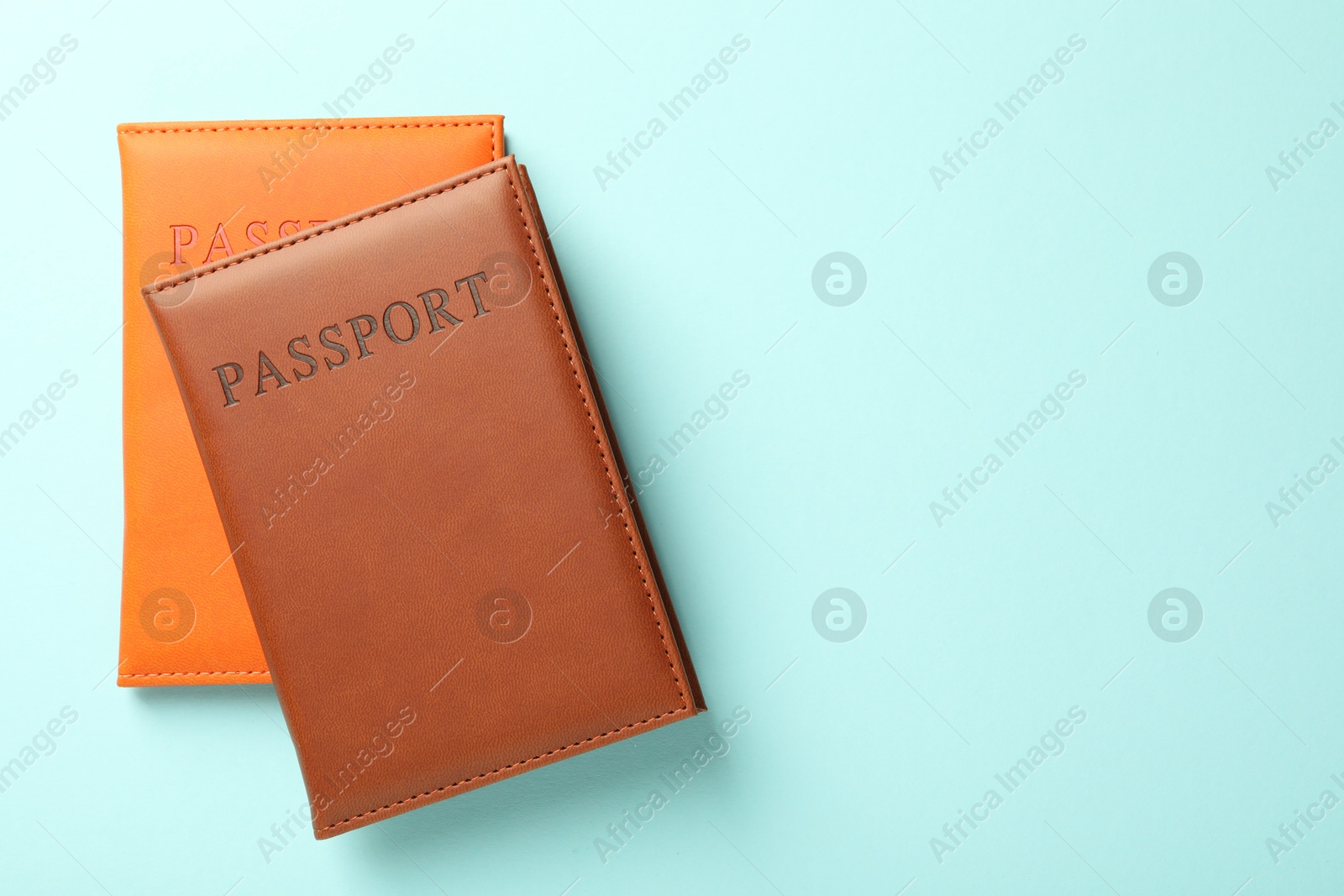 Photo of Passports in color covers on light blue background, top view. Space for text