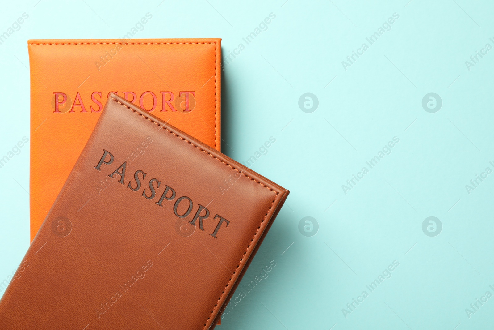 Photo of Passports in color covers on light blue background, top view. Space for text