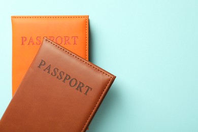 Photo of Passports in color covers on light blue background, top view. Space for text