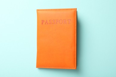 Photo of Passport in orange cover on light blue background, top view