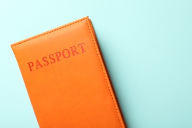 Photo of Passport in orange cover on light blue background, top view. Space for text