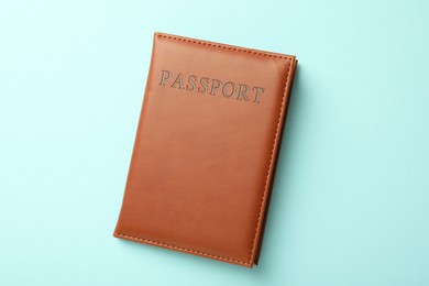 Photo of Passport in brown cover on light blue background, top view