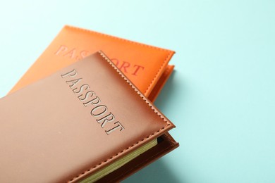 Photo of Passports in color covers on light blue background, closeup