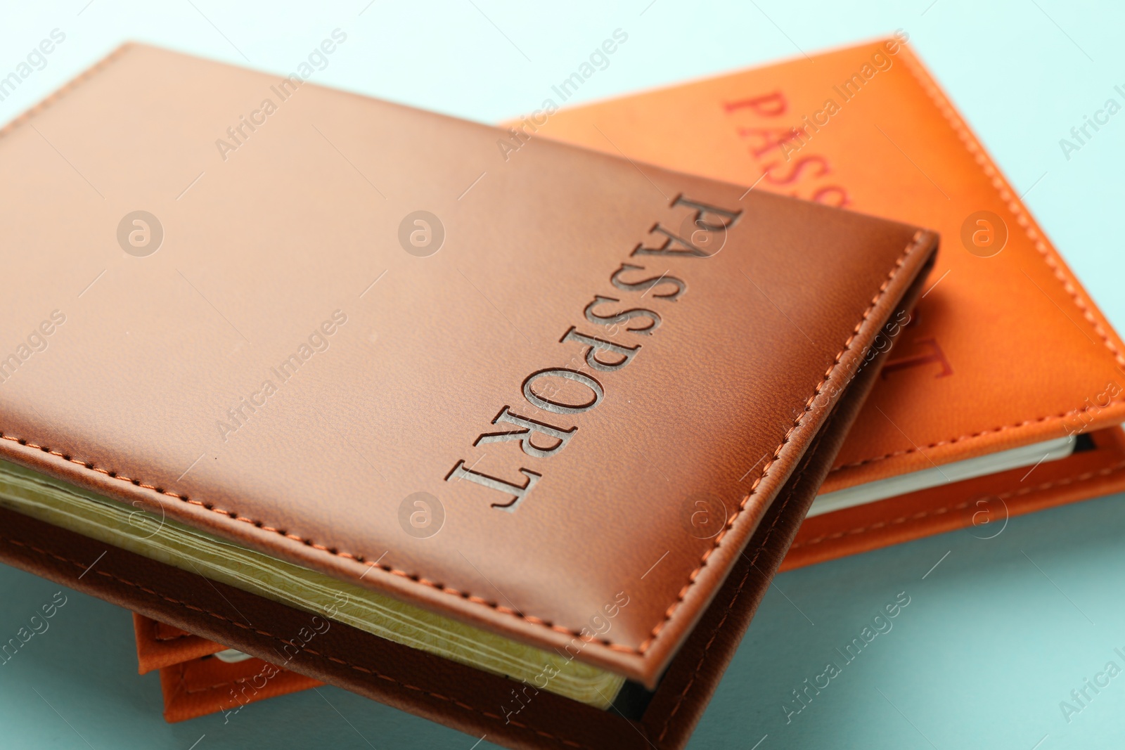 Photo of Passports in color covers on light blue background, closeup