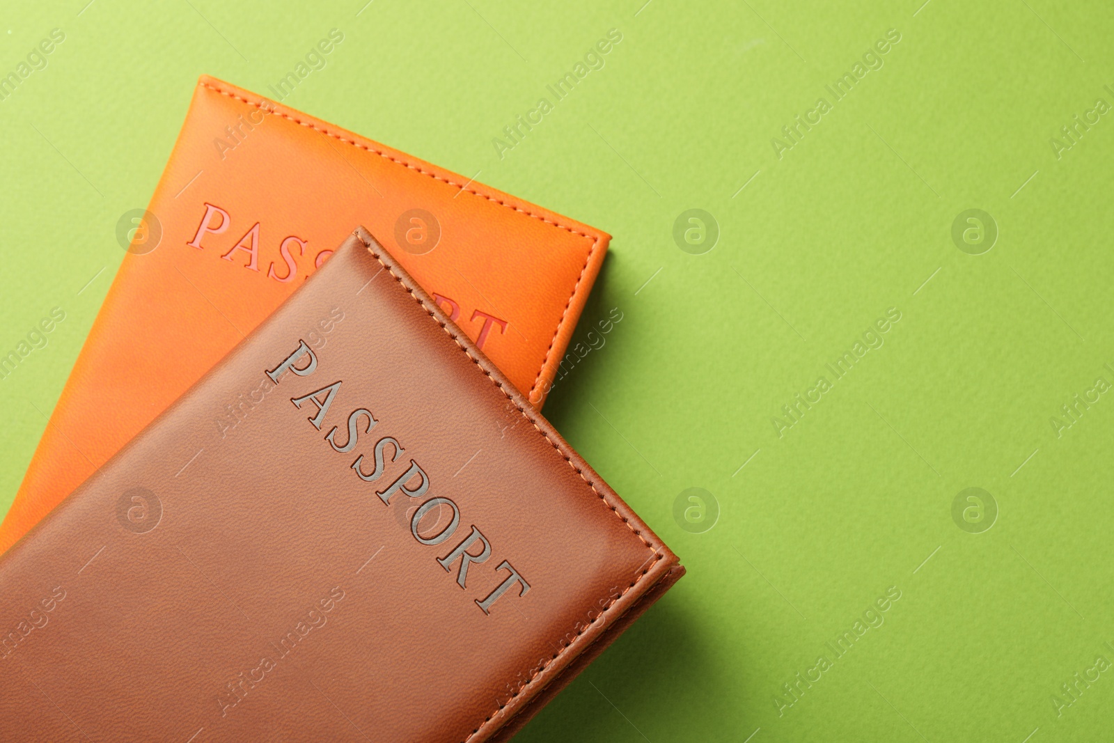 Photo of Passports in color covers on green background, top view. Space for text