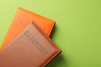 Passports in color covers on green background, top view. Space for text