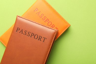 Photo of Passports in color covers on green background, top view. Space for text