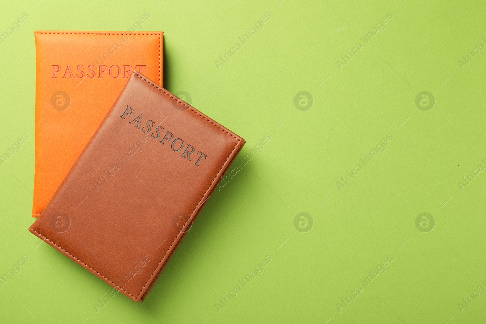 Photo of Passports in color covers on green background, top view. Space for text