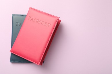 Photo of Passports in color covers on pink background, top view. Space for text