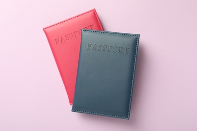 Photo of Passports in color covers on pink background, top view