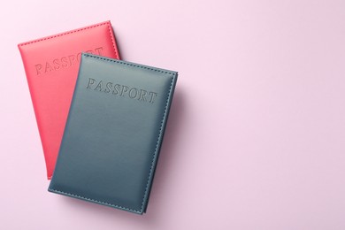 Photo of Passports in color covers on pink background, top view. Space for text