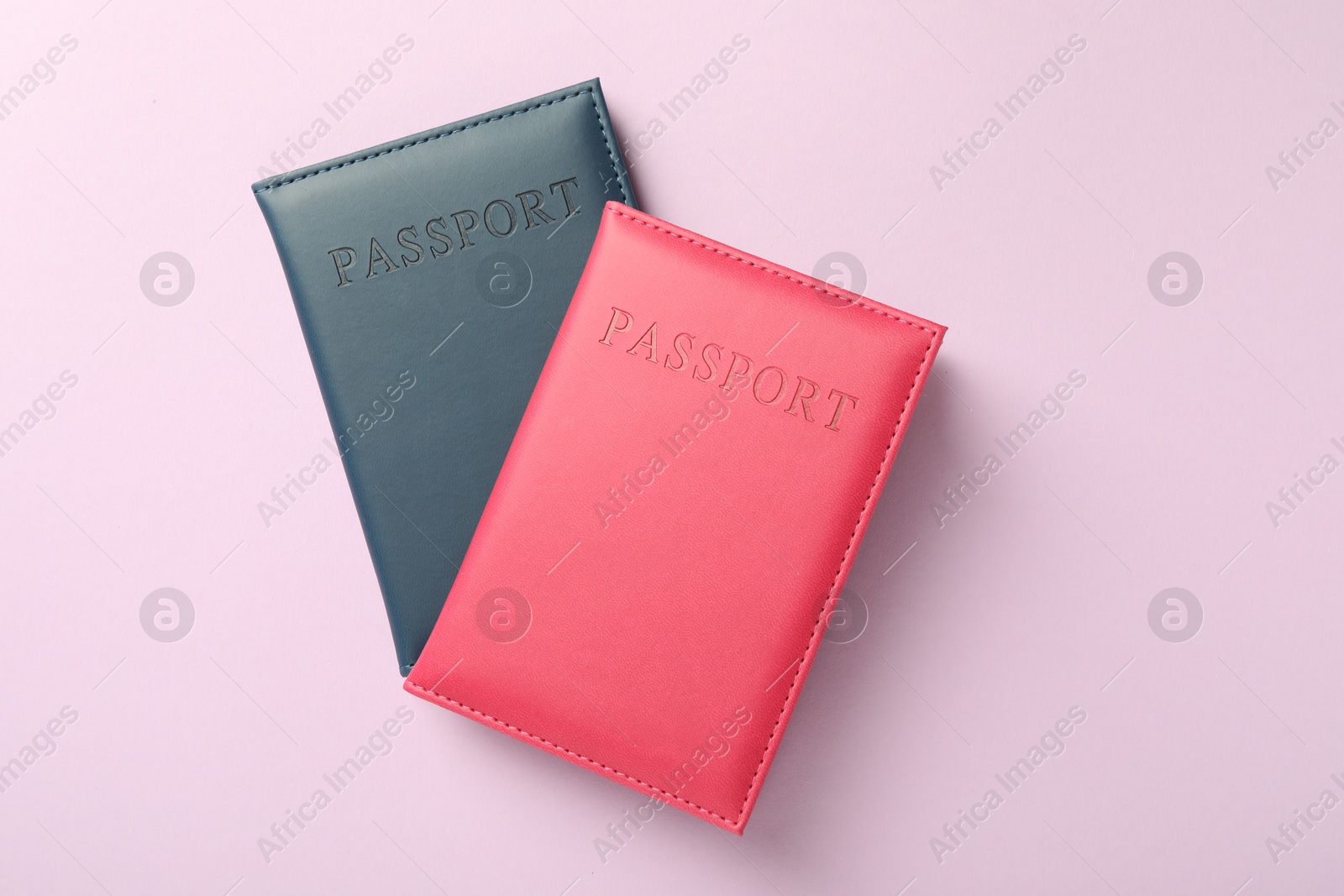 Photo of Passports in color covers on pink background, top view