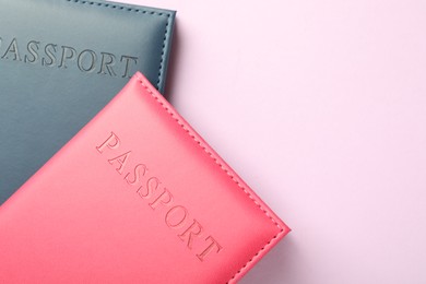 Photo of Passports in color covers on pink background, top view. Space for text