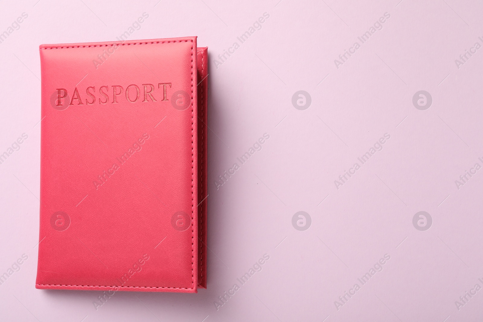 Photo of Passport in bright cover on pink background, top view. Space for text