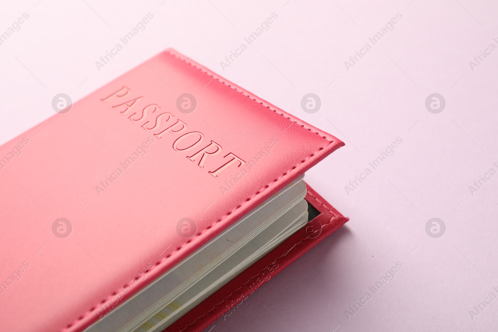 Photo of Passport in bright cover on pink background, closeup