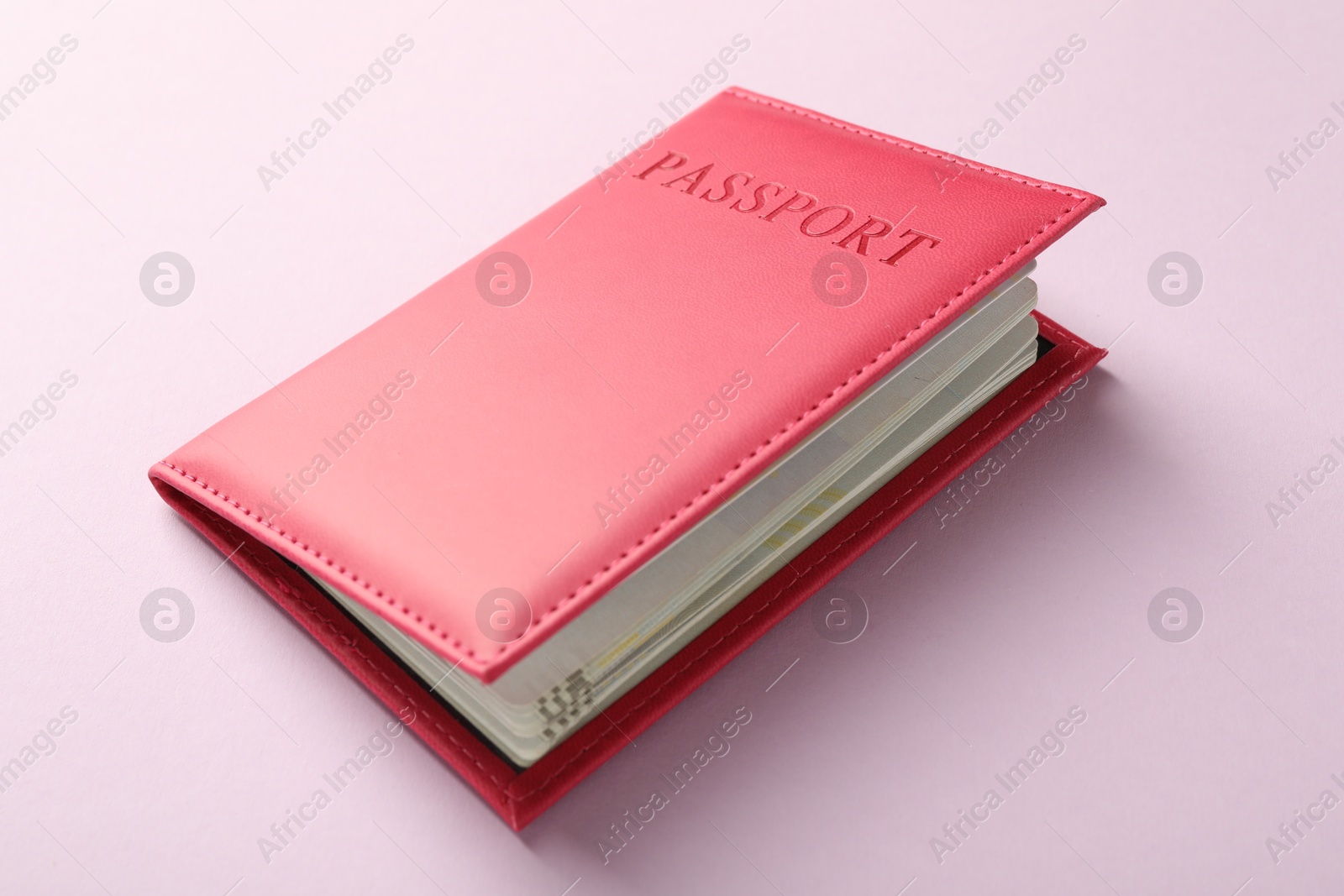 Photo of Passport in bright cover on pink background, closeup