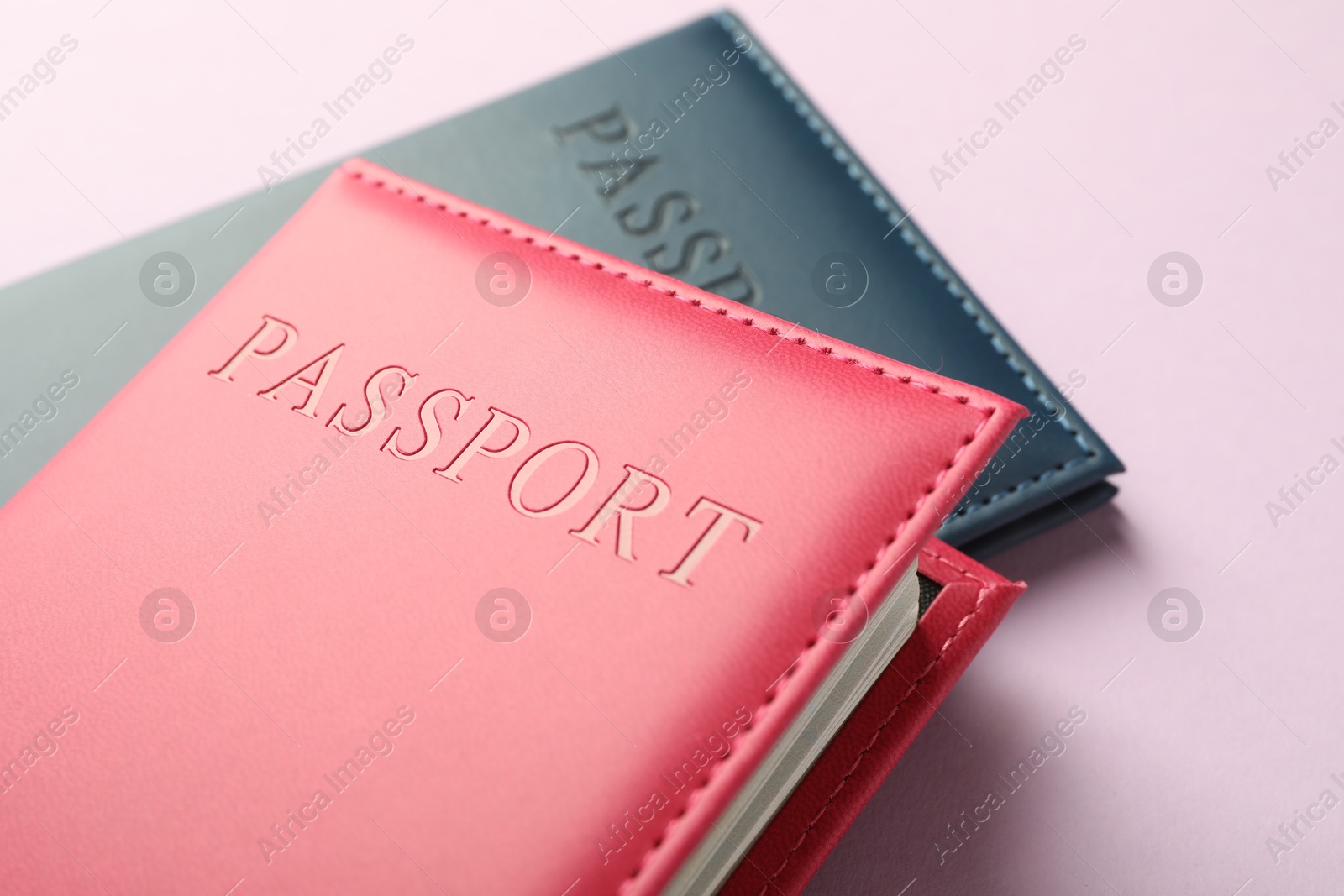 Photo of Passports in color covers on pink background, closeup