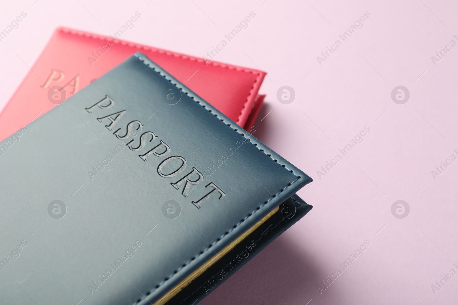 Photo of Passports in color covers on pink background, closeup. Space for text