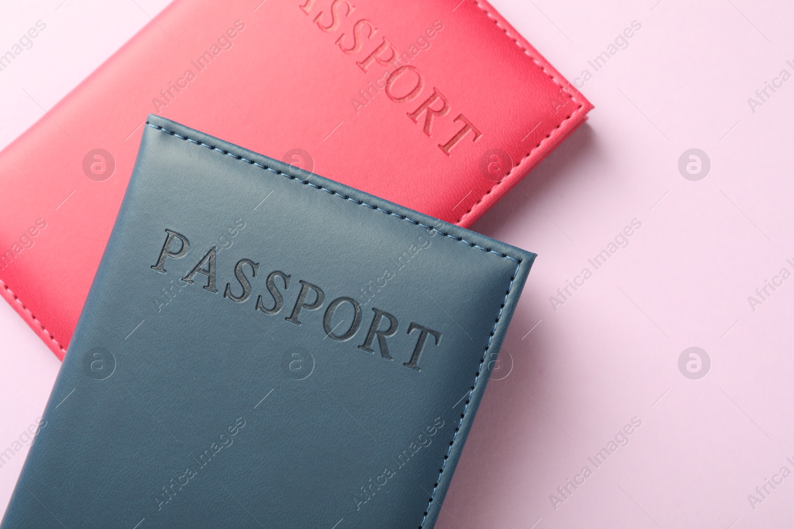 Photo of Passports in color covers on pink background, top view