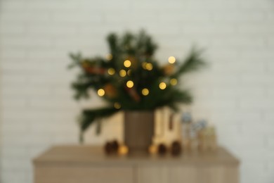 Blurred view of beautiful Christmas composition with decorated fir tree branches on wooden nightstand near white brick wall