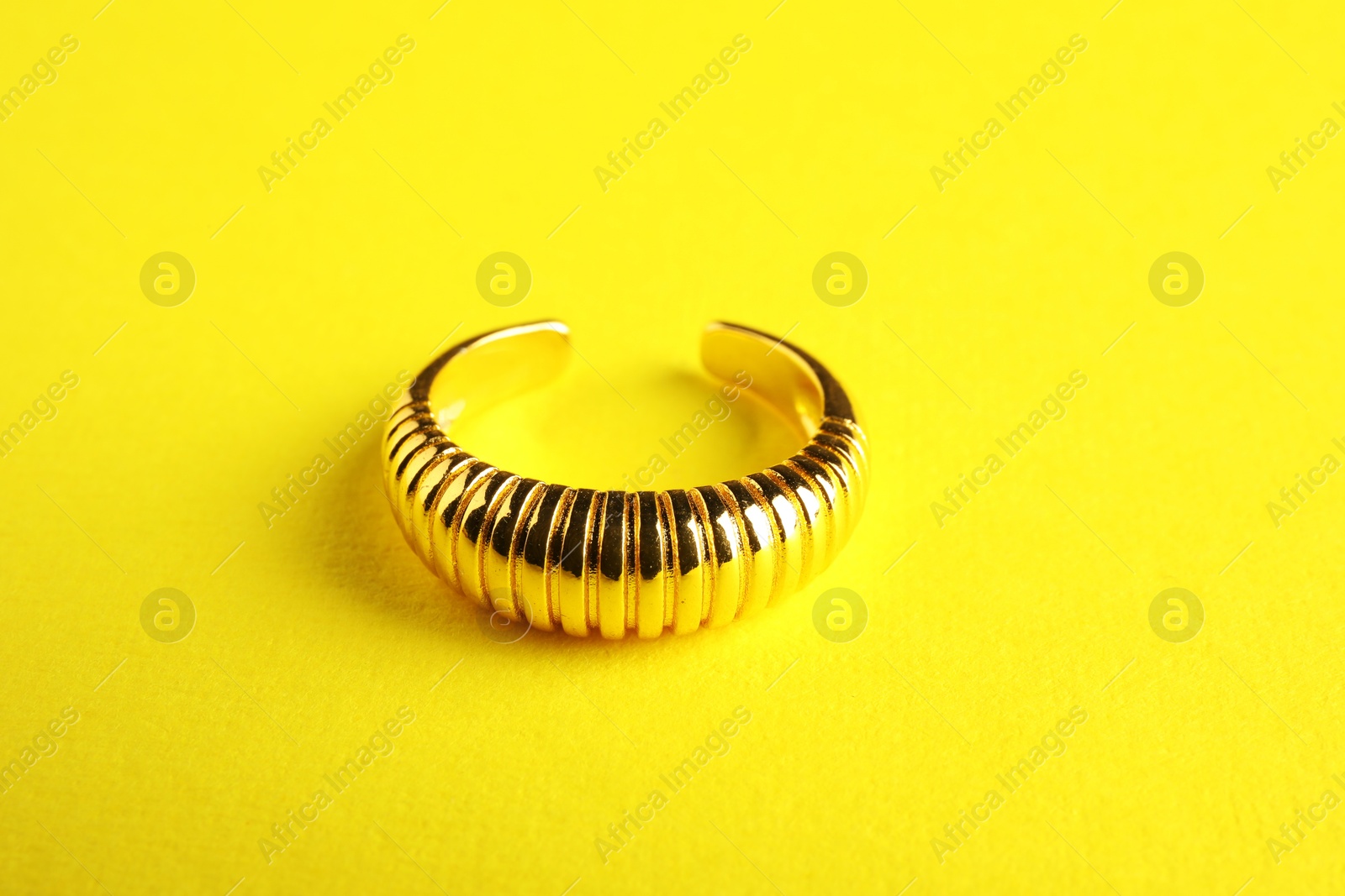 Photo of Beautiful bijouterie. Elegant ring on yellow background, closeup