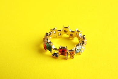 Photo of Beautiful bijouterie. Elegant ring on yellow background, closeup