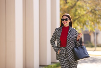 Photo of Smiling businesswoman in stylish suit outdoors on sunny day. Space for text