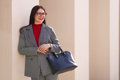 Smiling businesswoman in stylish suit outdoors on sunny day. Space for text