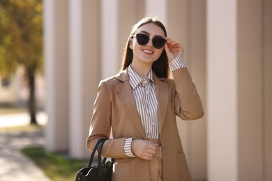 Photo of Portrait of smiling businesswoman in stylish suit outdoors