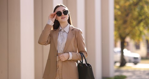 Businesswoman in stylish suit outdoors on sunny day